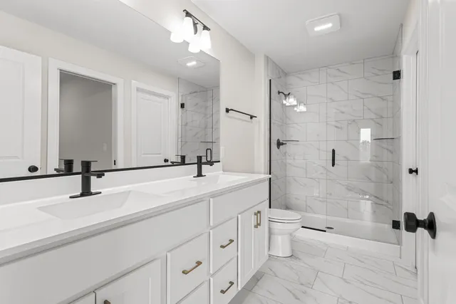 a bathroom with a double vanity sink toilet mirror and shower