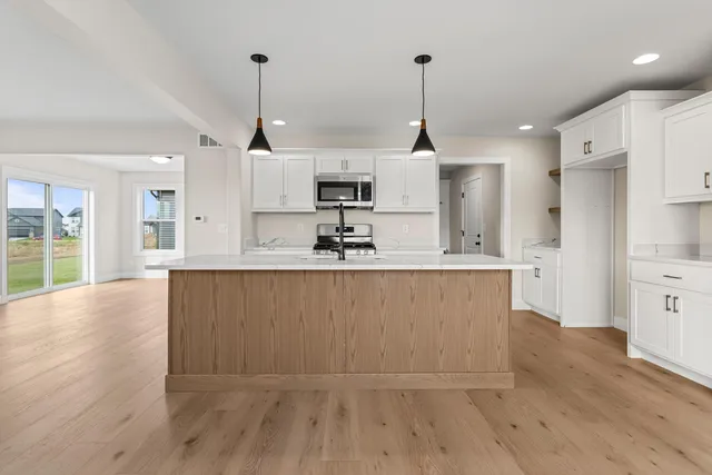 a kitchen with kitchen island a counter top space a sink stainless steel appliances and cabinets