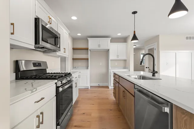 a kitchen with stainless steel appliances granite countertop a sink a stove and a refrigerator