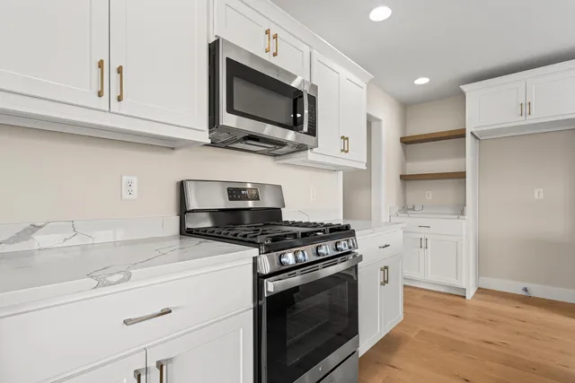 a kitchen with stainless steel appliances granite countertop a stove a microwave and a white cabinets