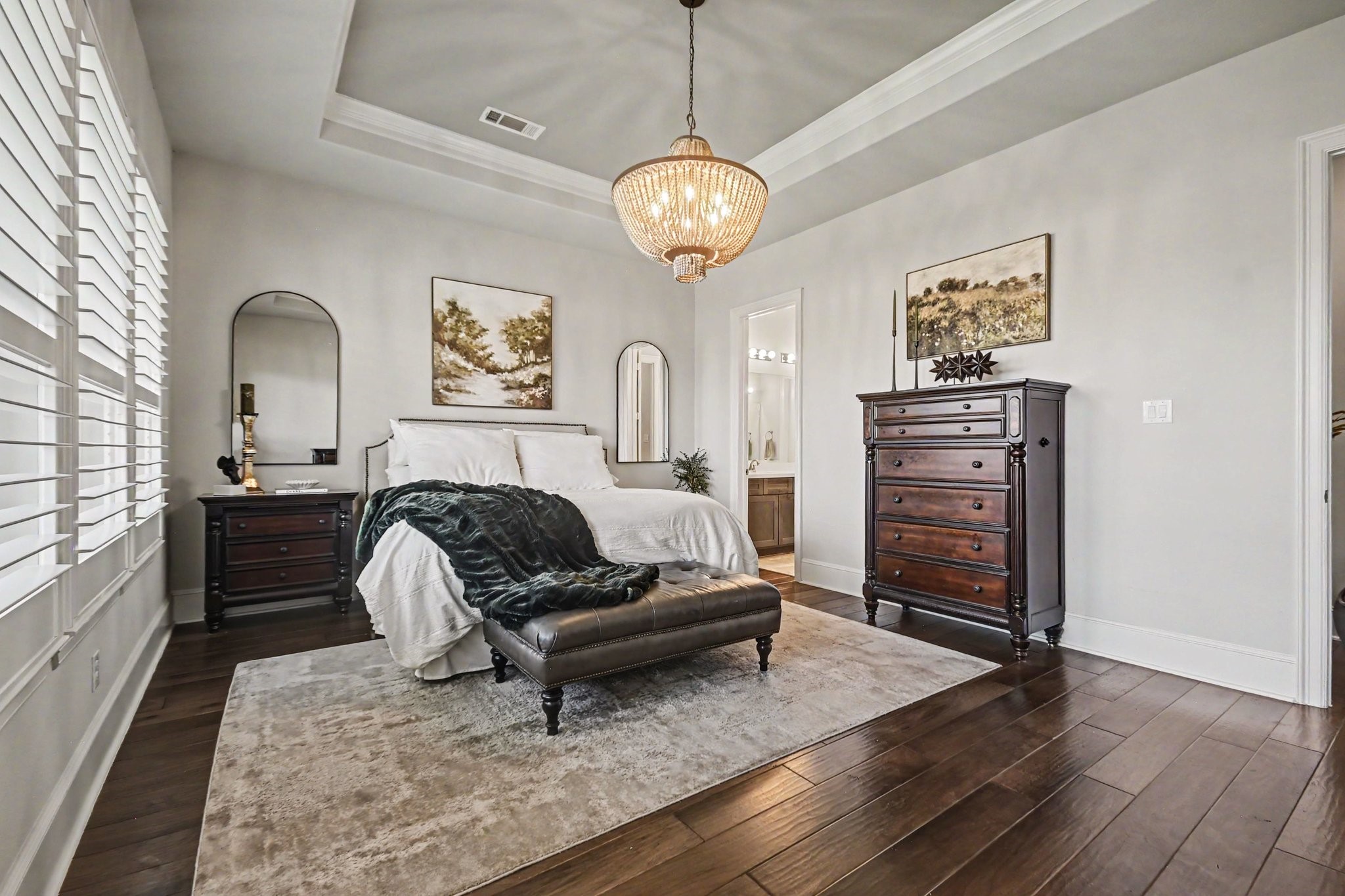 641 Kickapoo Court Webster, TX 77598 - Photo 20 of 39 This inviting primary bedroom features hardwood floors, a tray ceiling with a stylish chandelier, and large windows with beautiful plantation shutters.