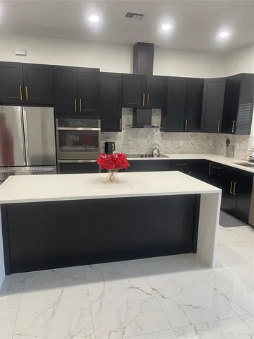 a large kitchen with stainless steel appliances a stove a sink and a microwave