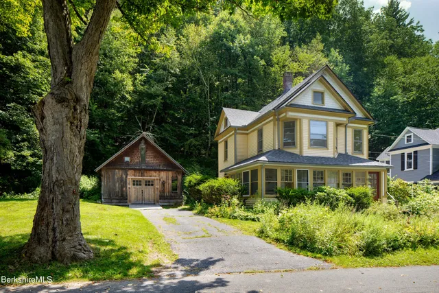 a front view of a house with a yard and trees
