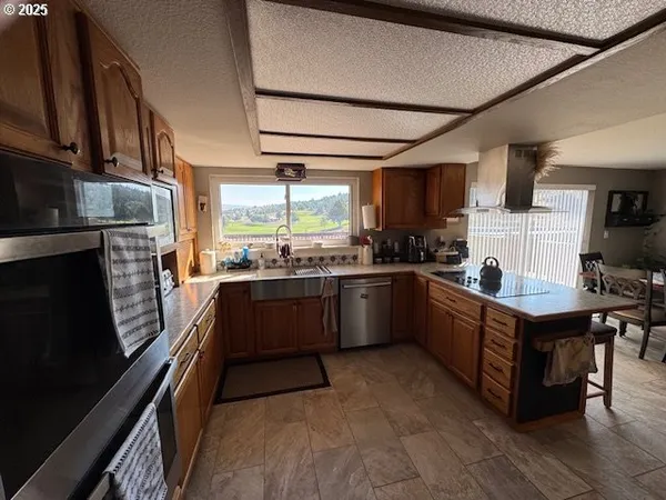 a kitchen with stainless steel appliances a sink cabinets and a window