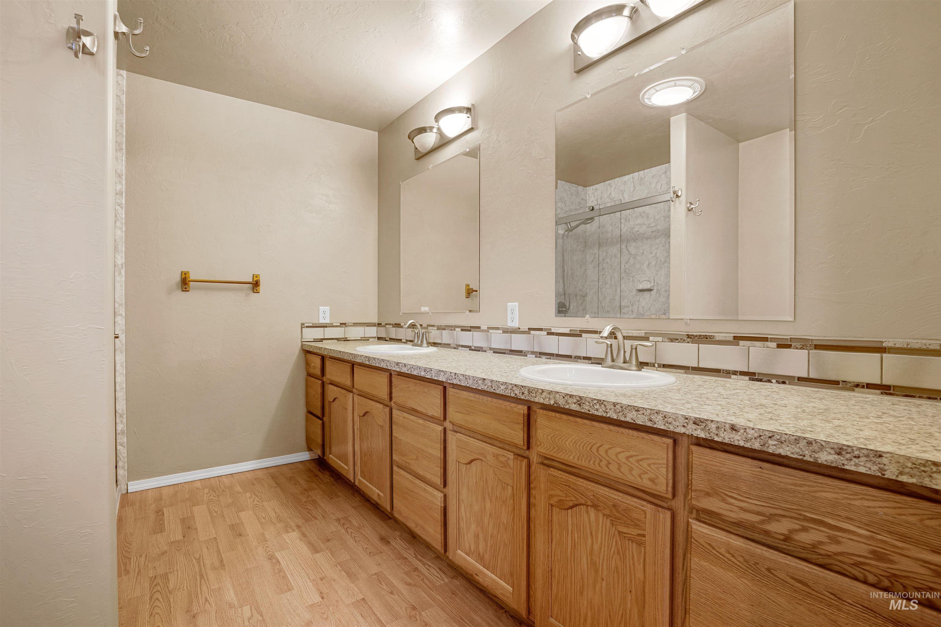 720 East Main Street Jerome, ID 83338 - Photo 13 of 50 Full bath with double vanity, light wood-type flooring, and a shower stall
