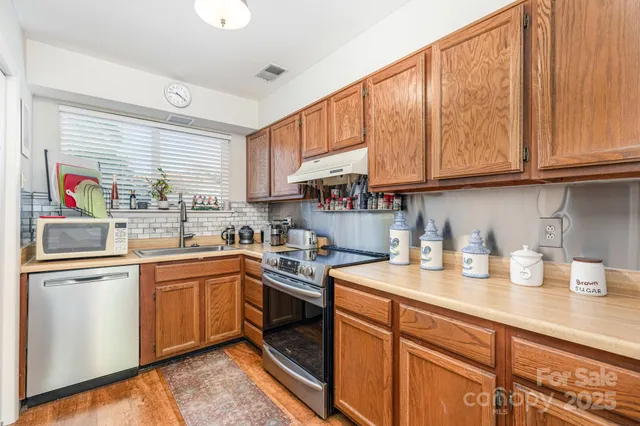 a kitchen with stainless steel appliances granite countertop a sink window and cabinets