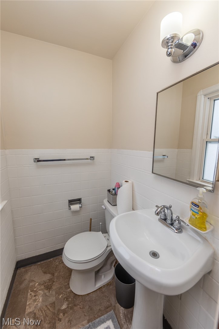 7433 Pearl Road Cleveland, OH 44130 - Photo 6 of 28 Bathroom with sink, mirror, tile flooring, tile walls, and backsplash