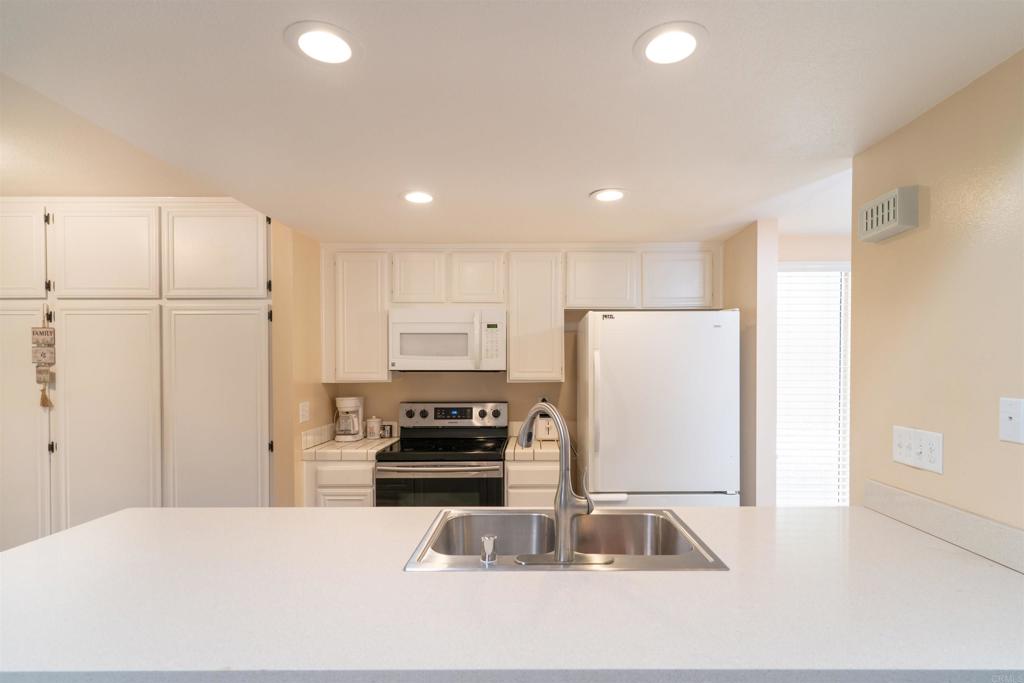 23691 Country Villa Road Ramona, CA 92065 - Photo 3 of 22 a kitchen with kitchen island granite countertop a refrigerator a stove a sink and white countertops with wooden floor