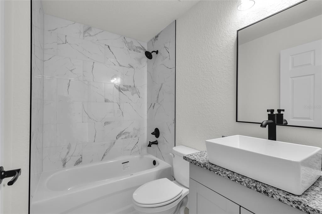 23711 Southwest Rainbow Lakes Boulevard Dunnellon, FL 34431 - Photo 14 of 27 a bathroom with a bathtub shower sink vanity mirror and toilet