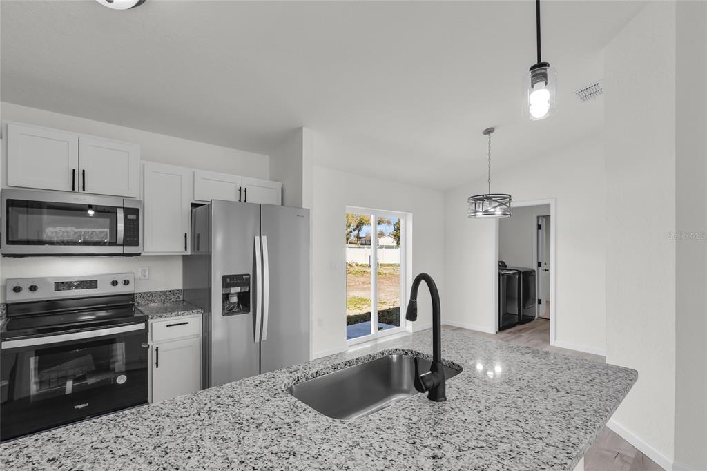 23711 Southwest Rainbow Lakes Boulevard Dunnellon, FL 34431 - Photo 24 of 27 a kitchen with stainless steel appliances granite countertop a sink stove and refrigerator