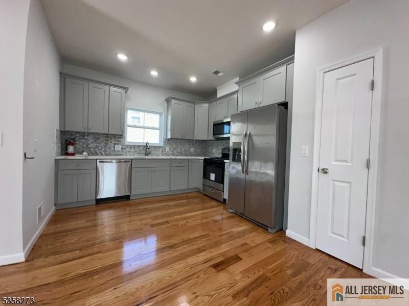 476 Meade Street, Unit 1A Orange, NJ 07050 - Photo 3 of 11 a kitchen with stainless steel appliances granite countertop a refrigerator a sink dishwasher and a oven with wooden floor