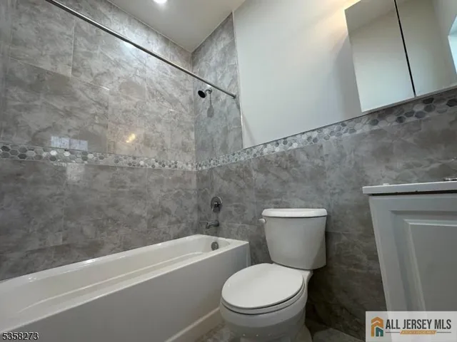 a white toilet sitting next to a bath tub and a shower