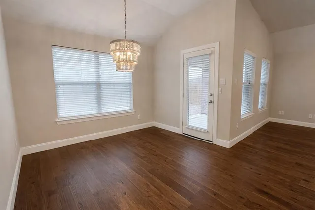 a view of an empty room and chandelier fan