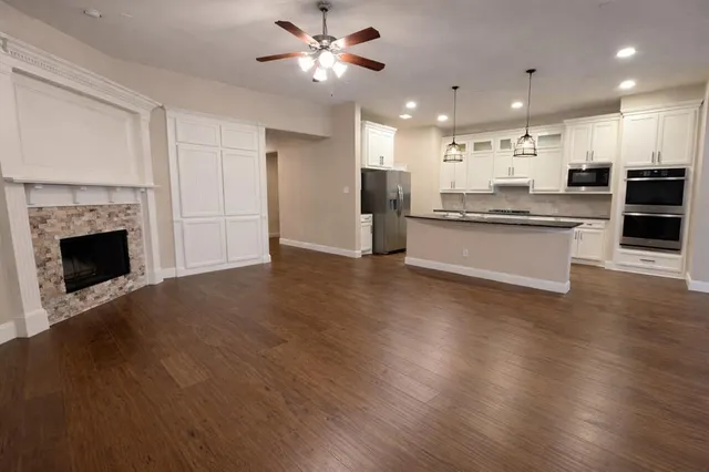 a kitchen with stainless steel appliances granite countertop wooden floors and wide window