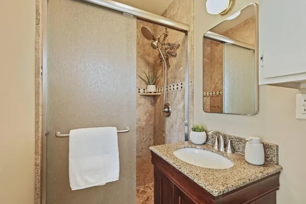 a bathroom with a granite countertop sink a mirror and a shower