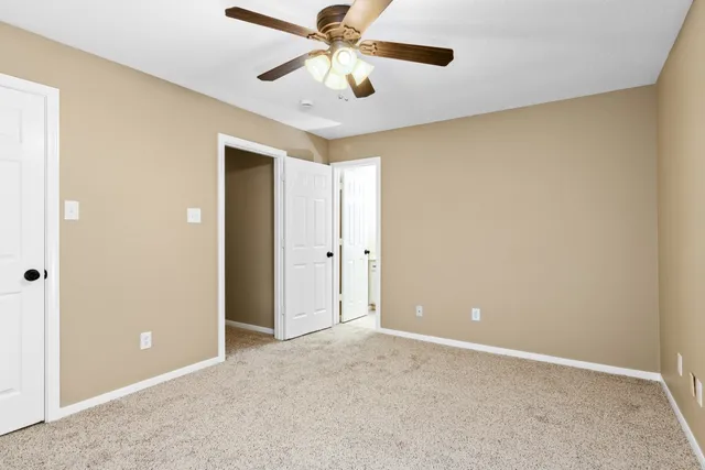 an empty room with closet and a chandelier fan