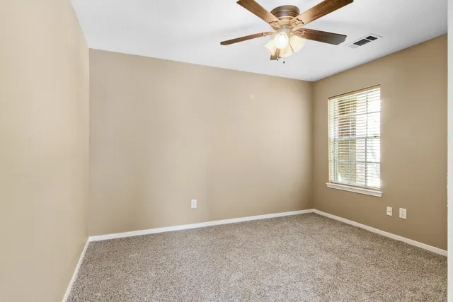 an empty room with a window and a fan