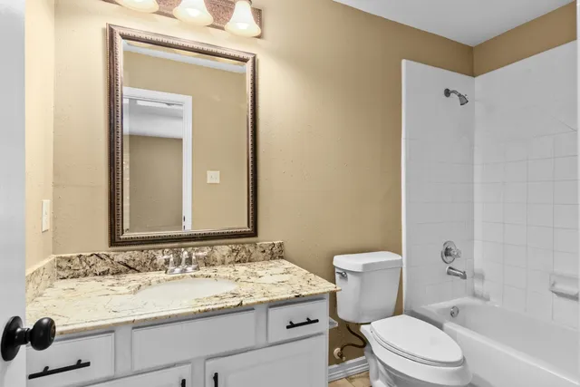a bathroom with a granite countertop sink toilet and shower