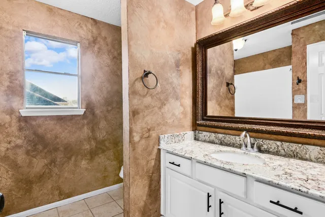a bathroom with a granite countertop sink and a mirror