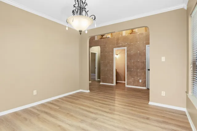 a view of a hallway with wooden floor and a chandelier