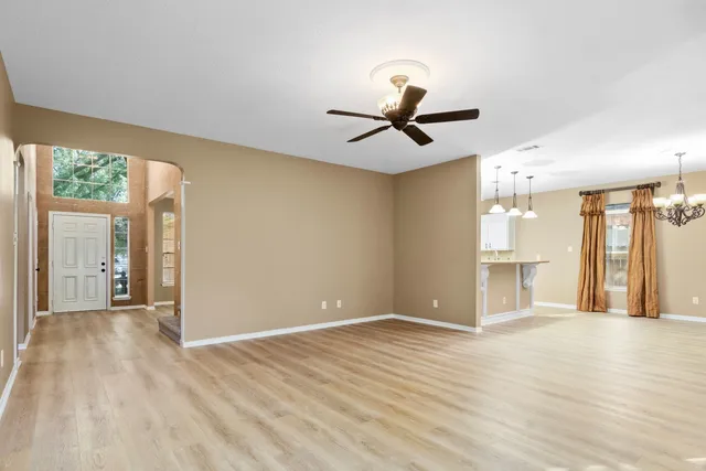 a view of a big room with wooden floor a ceiling fan and windows