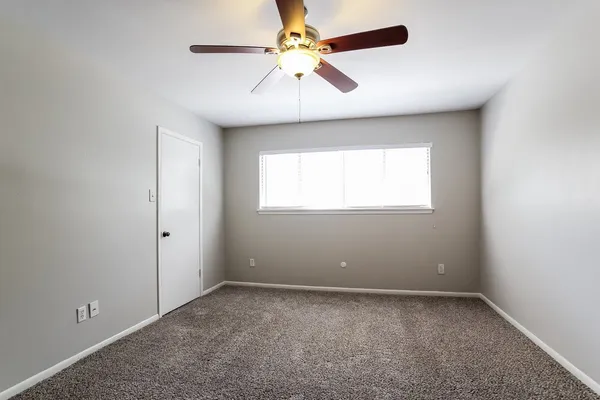 an empty room with a window and a fan