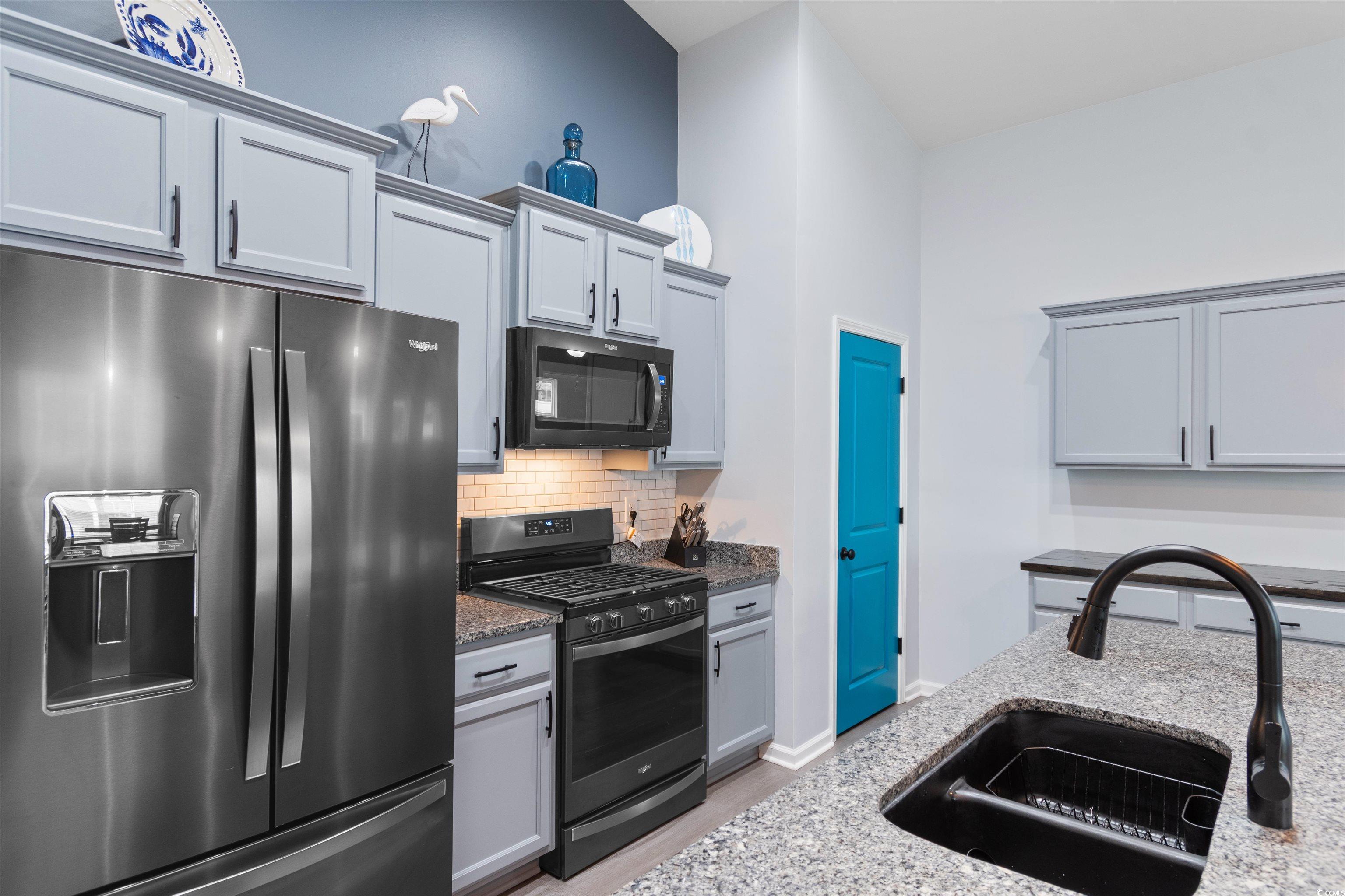 4380 Livorn Loop, Unit 4380 Myrtle Beach, SC 29579 - Photo 6 of 33 Kitchen with stainless steel appliances, a kitchen bar, light stone countertops, gray cabinets, and a kitchen island with sink