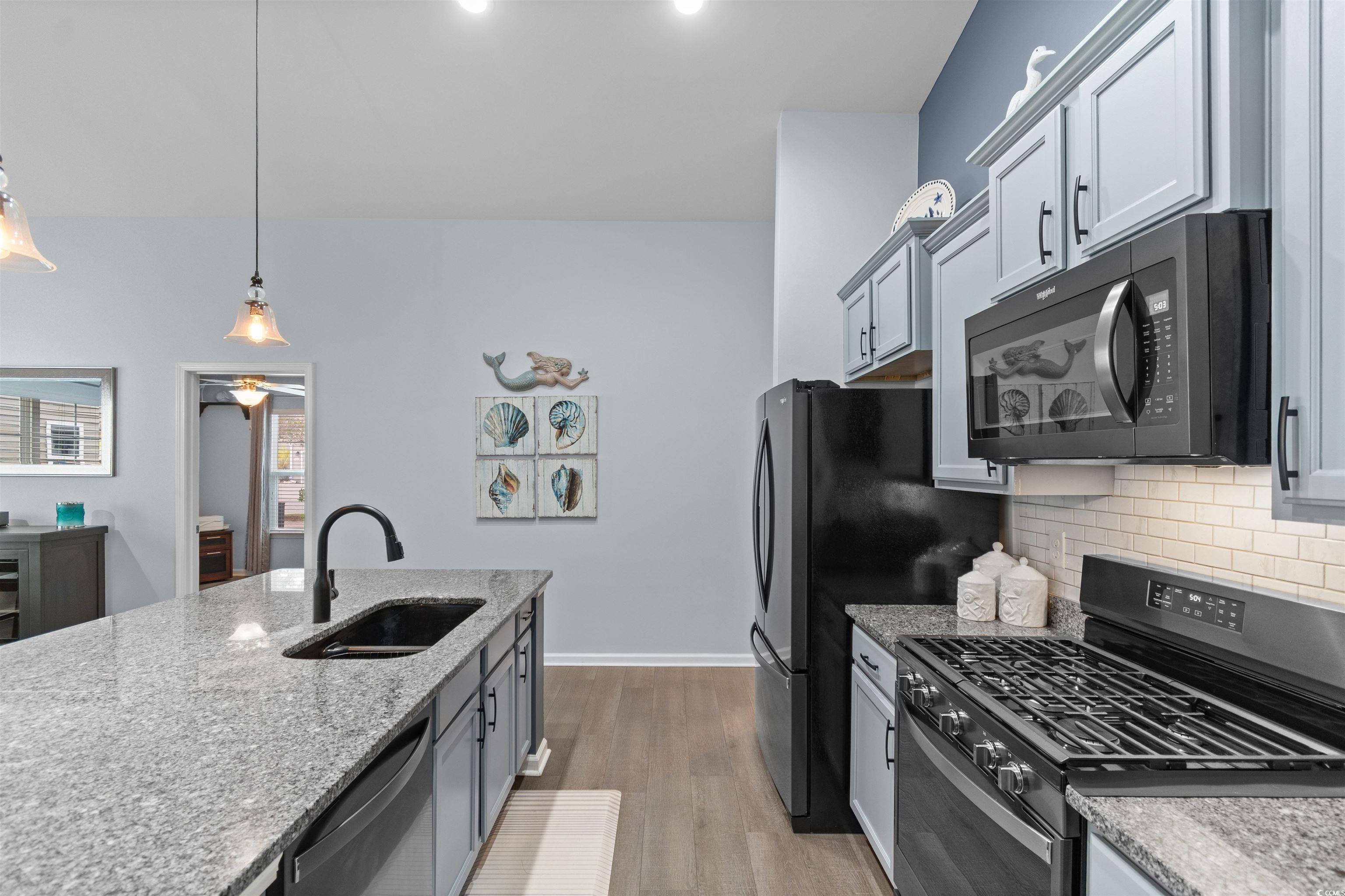 4380 Livorn Loop, Unit 4380 Myrtle Beach, SC 29579 - Photo 7 of 33 Kitchen featuring gray cabinetry, vaulted ceiling, light wood-type flooring, hanging light fixtures, and a kitchen island with sink