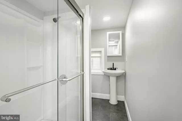 a bathroom with a sink a toilet a mirror and shower