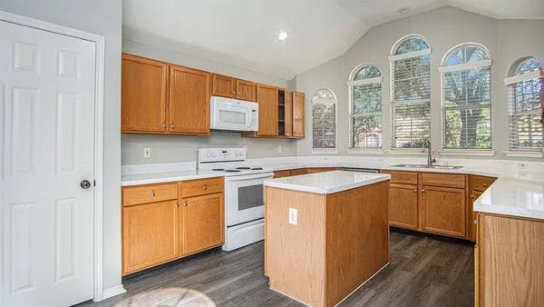 a kitchen with stainless steel appliances granite countertop a sink and cabinets with wooden floor