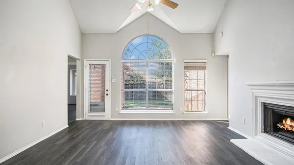 an empty room with wooden floor fireplace and windows