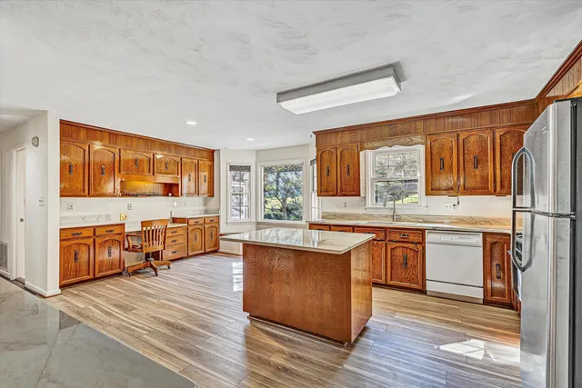 a kitchen with stainless steel appliances granite countertop a refrigerator a oven a sink with wooden floors and cabinets