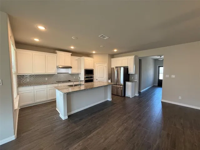 a kitchen with stainless steel appliances granite countertop a refrigerator and a stove top oven