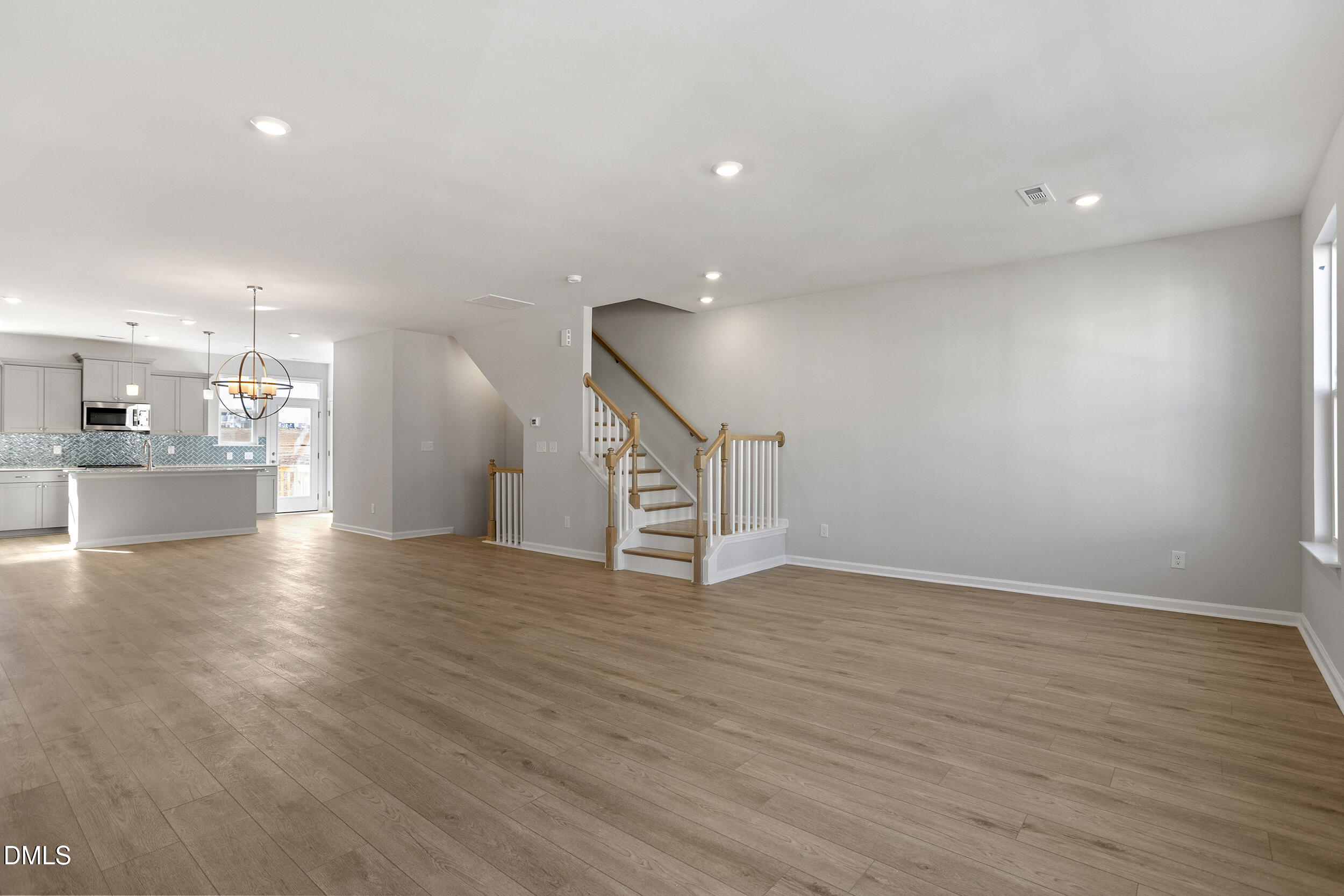 367 Chesapeake Commons Street, Unit 115 Garner, NC 27529 - Photo 9 of 43 a view of an empty room with wooden floor and a kitchen