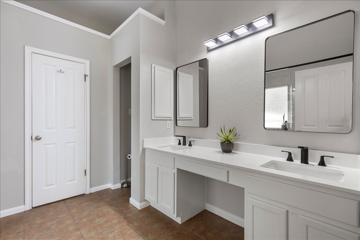 9012 Meacham Way Austin, TX 78749 - Photo 19 of 34 Dual vanity with white cabinetry and countertops, matte black fixtures, rectangular mirrors, and overhead lighting