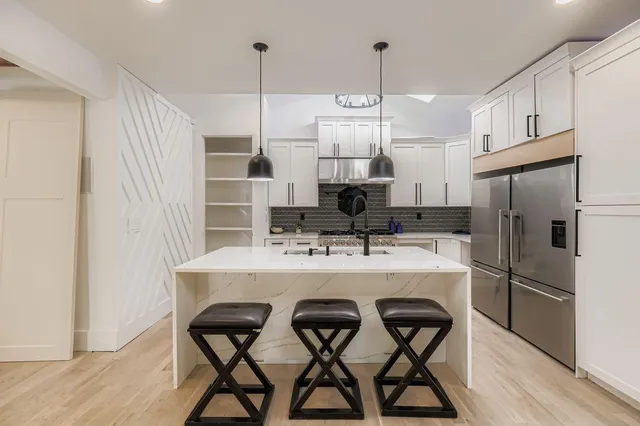 a kitchen with stainless steel appliances a table and chairs in it
