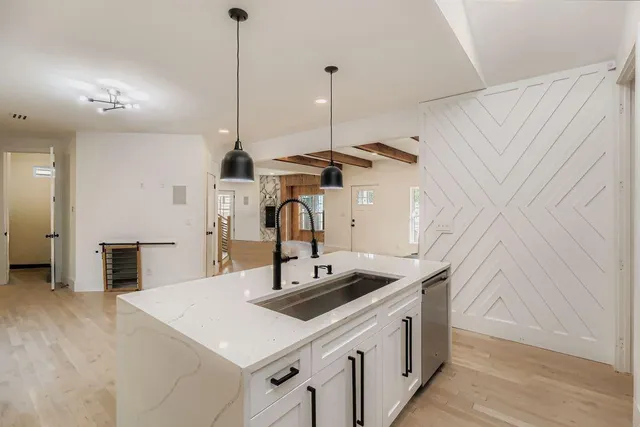 a kitchen that has a sink a stove and a wooden floor