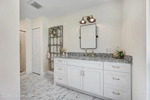 a bathroom with a granite countertop sink and a mirror