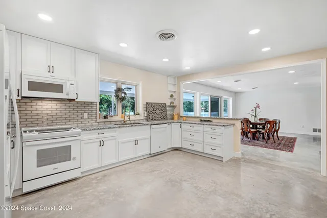 a large white kitchen with white cabinets and stainless steel appliances