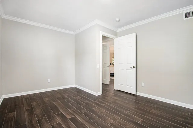a view of an empty room with wooden floor and windows