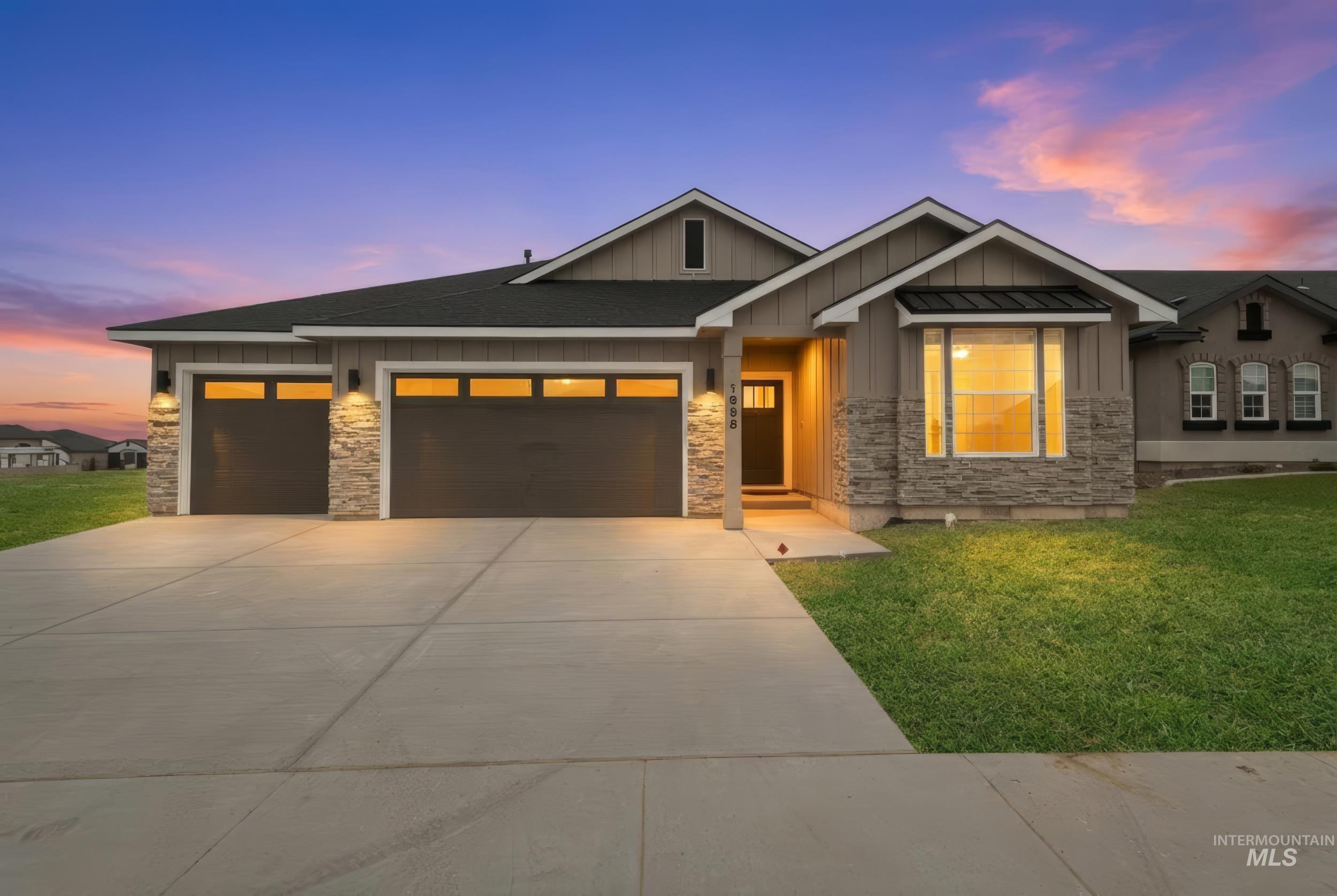View of front of property featuring board and batten siding, a front lawn, stone siding, and an attached garage