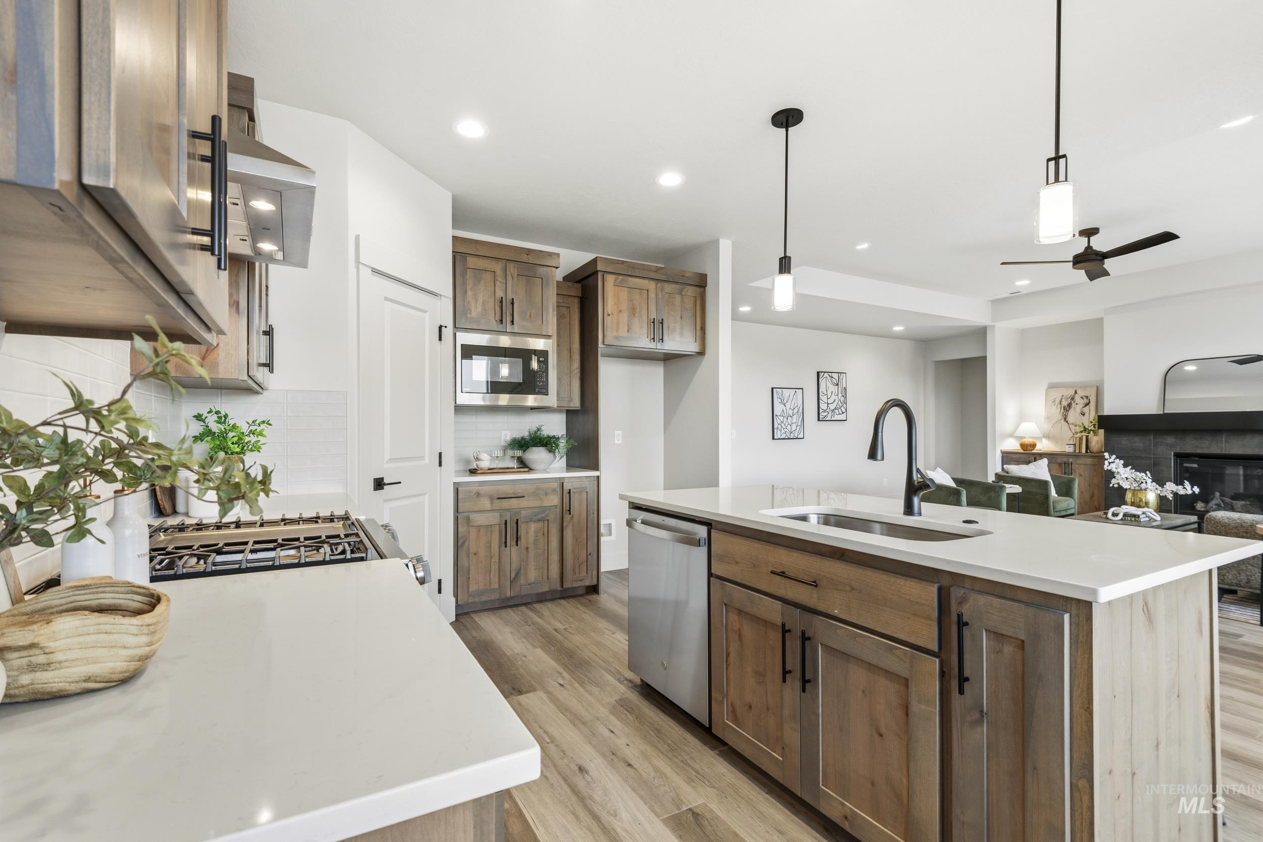 1988 West Bittern Street Nampa, ID 83686 - Photo 19 of 34 Kitchen featuring pendant lighting, ceiling fan, a glass covered fireplace, light wood-style flooring, and an island with sink