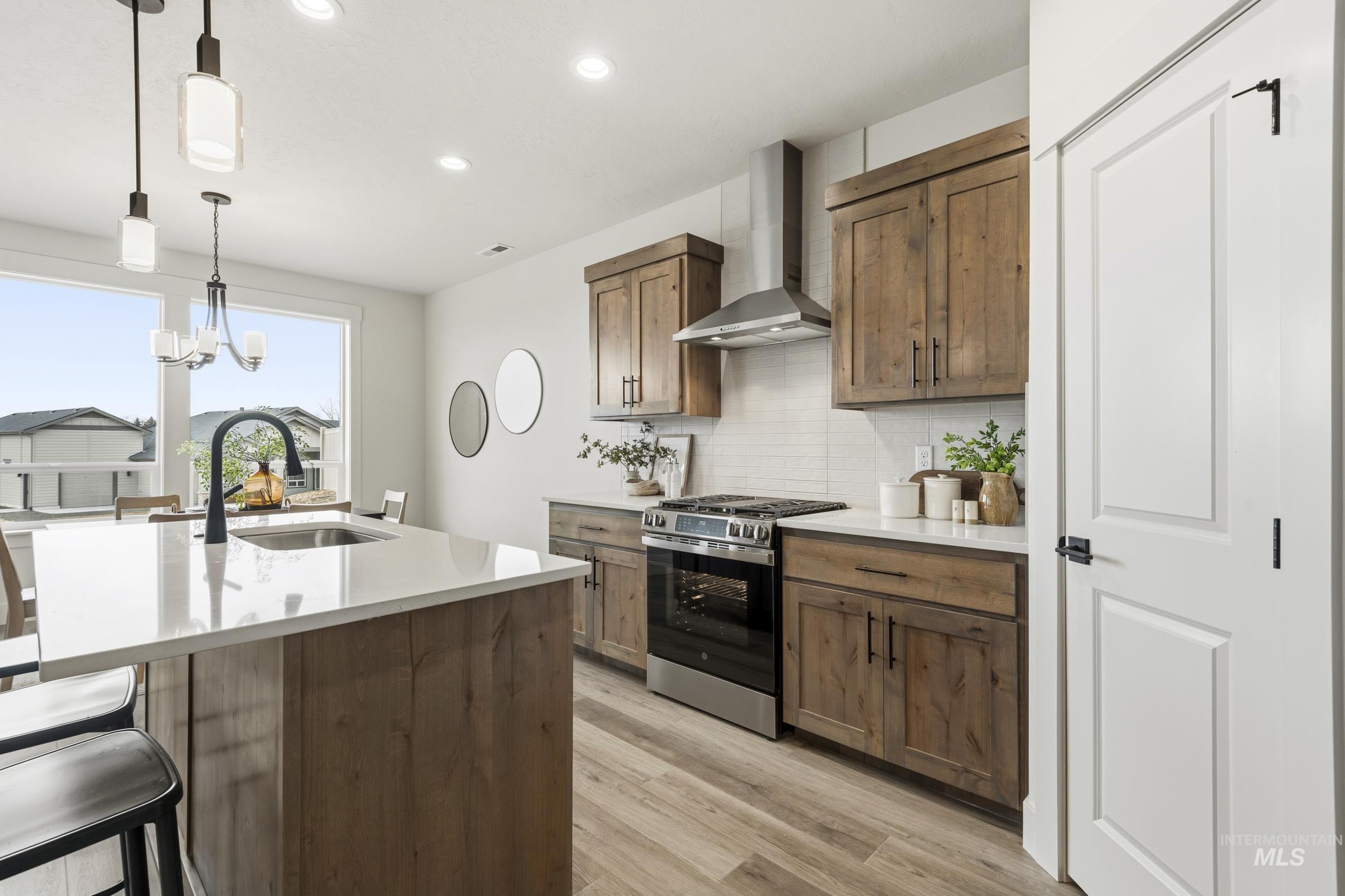 1988 West Bittern Street Nampa, ID 83686 - Photo 20 of 34 Kitchen with stainless steel gas stove, light wood-type flooring, hanging lights, light stone countertops, and an island with sink
