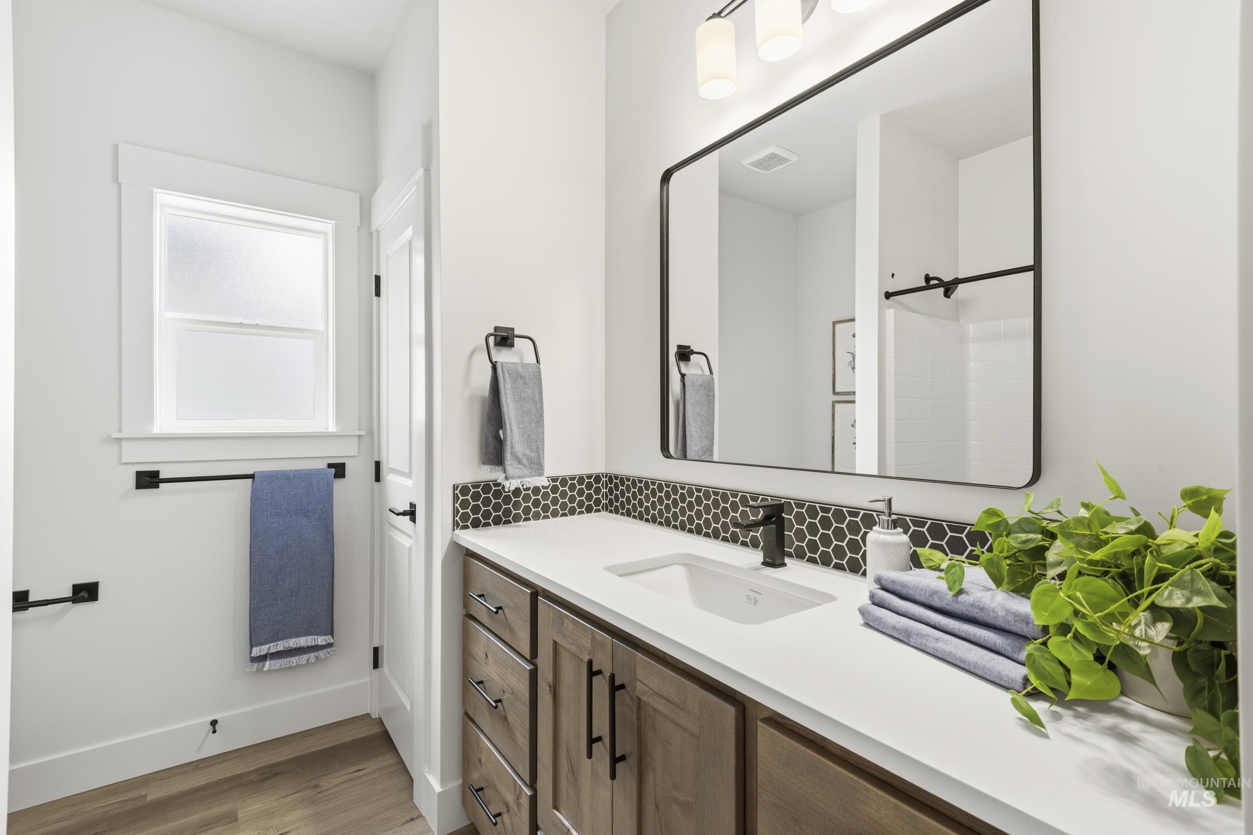 1988 West Bittern Street Nampa, ID 83686 - Photo 8 of 34 Bathroom with vanity, light wood-style flooring, a shower, and tasteful backsplash