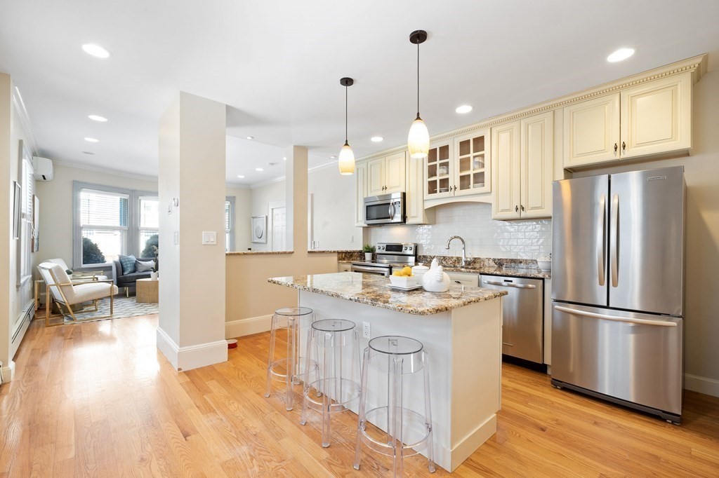 12 Colliston Road, Unit 2 Boston, MA 02135 - Photo 3 of 10 a kitchen with stainless steel appliances granite countertop a sink a stove a refrigerator and island with wooden floor
