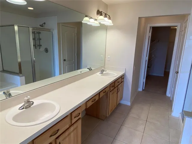 a spacious bathroom with a double vanity sink a mirror and a shower