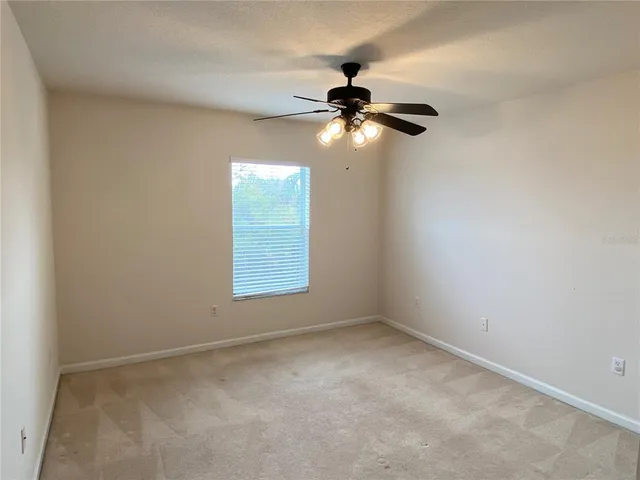 an empty room with a chandelier fan and windows