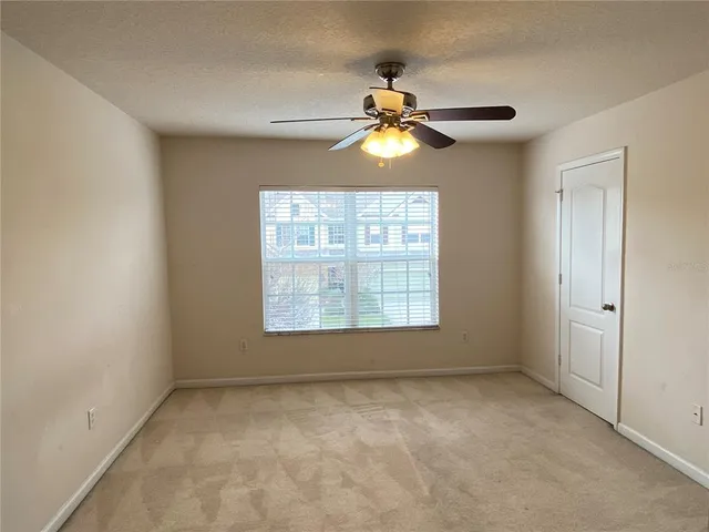 an empty room with windows and fan