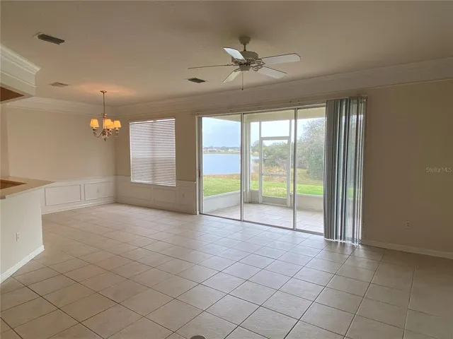 an empty room with chandelier fan and windows