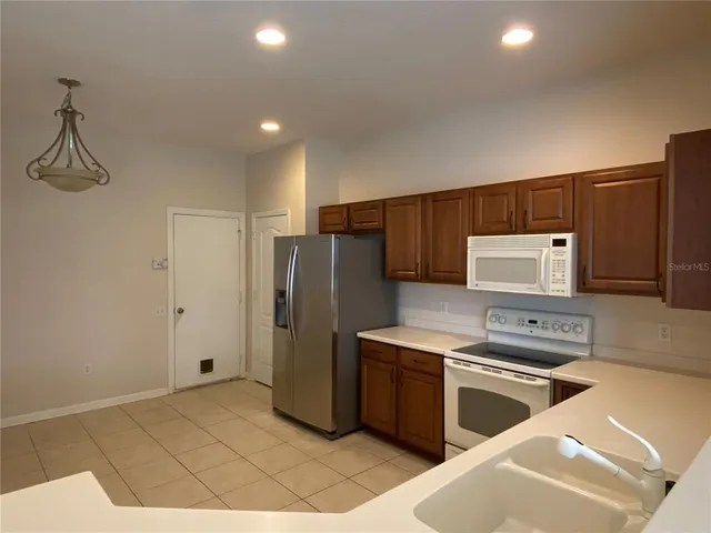 a kitchen with granite countertop a refrigerator and a stove top oven